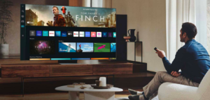 Image of a young man watching TV and probably using a streaming bundle through his CTV to have access to different SVOD and AVOD services.