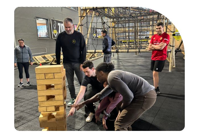 Beatgrid team members participating in a team-building exercise, playing a giant Jenga game indoors.